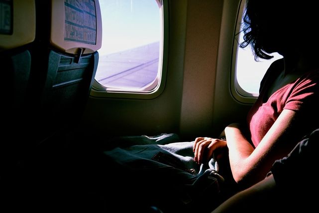 飛行機の窓側の席に座る女性