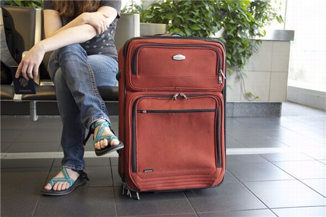 女性の横に置かれたソフトタイプのスーツケース