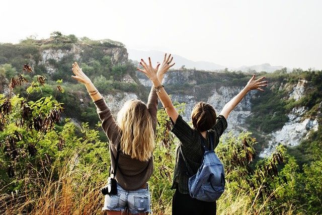 山の頂上で両手を上げる2人の女性
