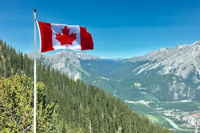 カナディアンロッキーを背景に立てられたカナダの国旗